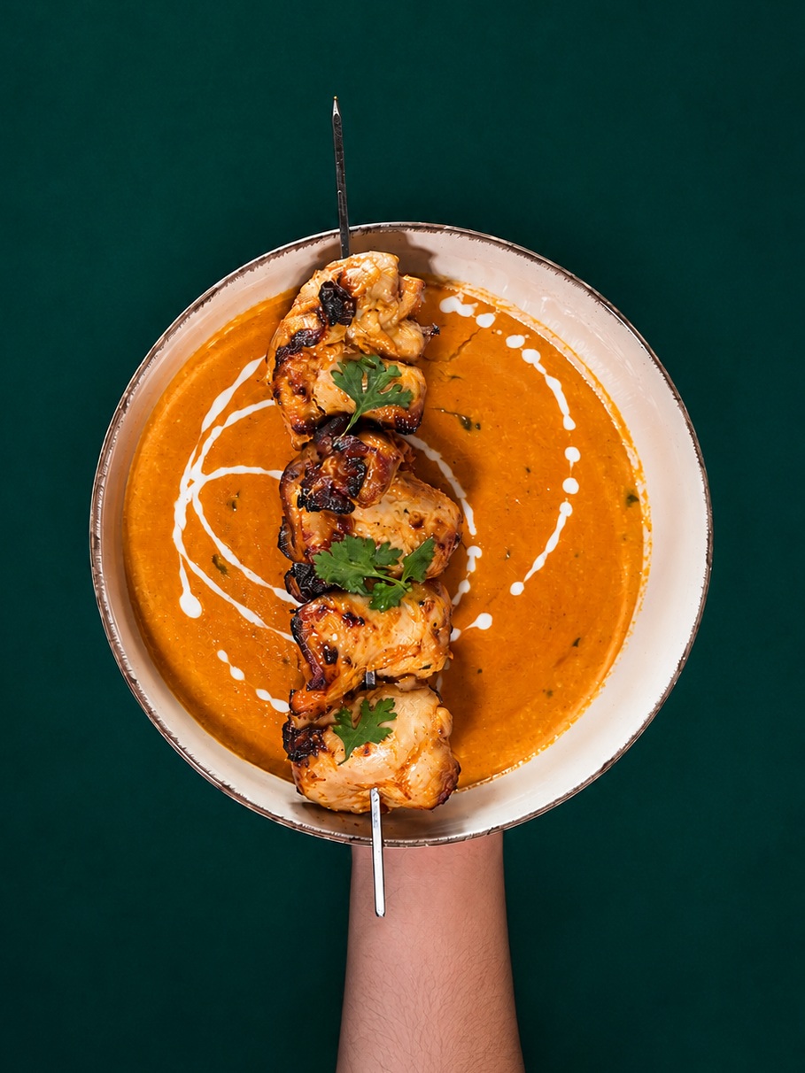 Chicken skewers over a creamy saffron curry, finished with cream and coriander
